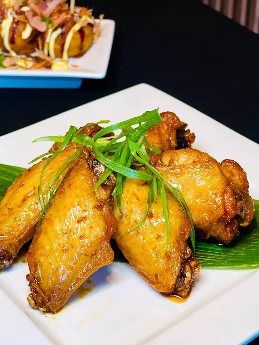 Chicken wings coated in a soy garlic sauce, topped with sliced green onions at Kinya, a Japanese Restaurant in Gainesville